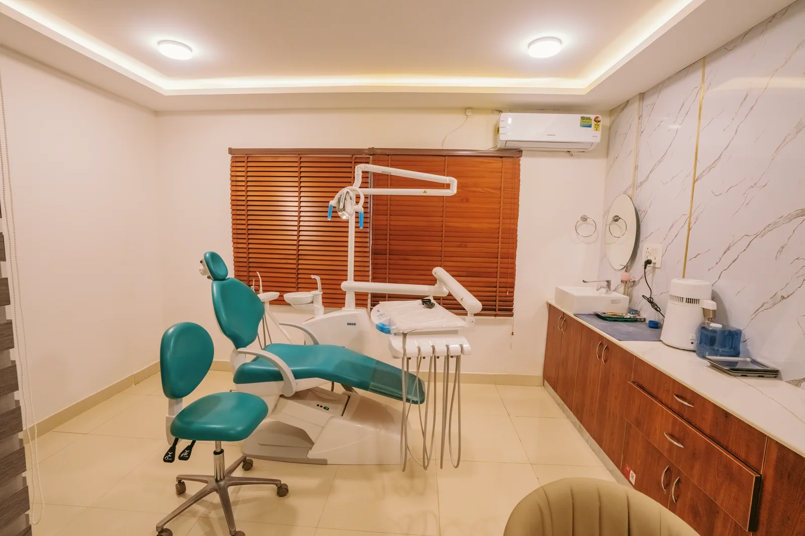 Dental operatory by Candidscape at Apollo Clinic, New BEL Road, Bangalore, with a teal dental chair, wooden cabinetry and a wash basin