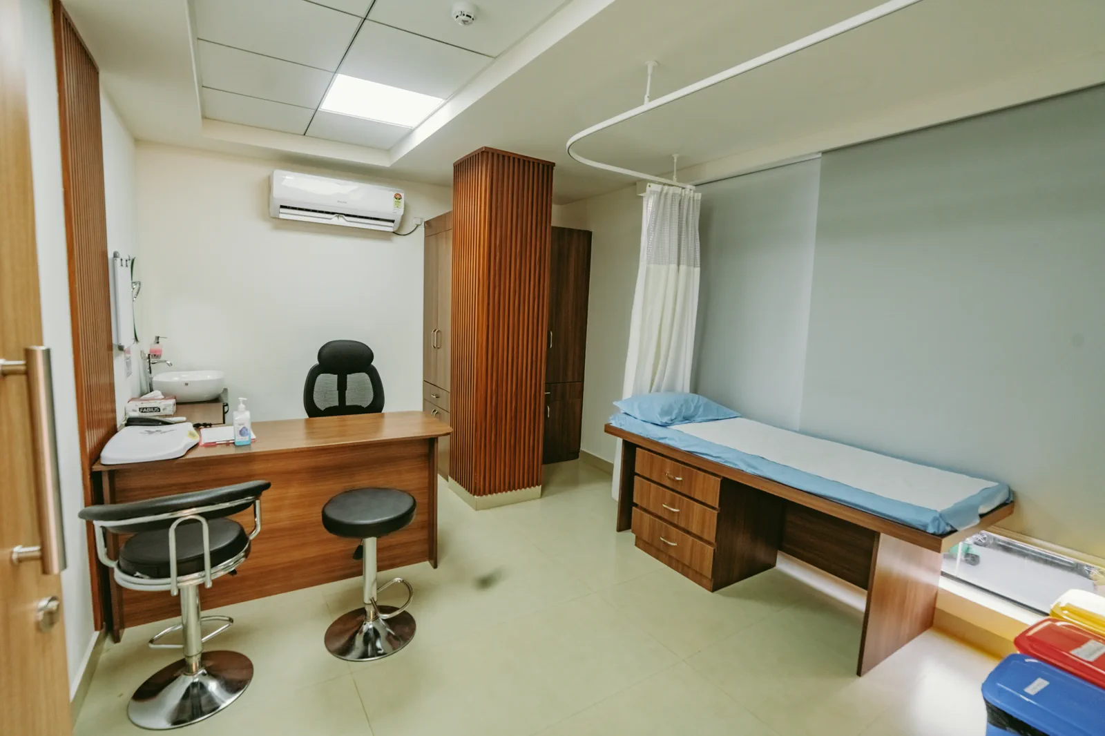 Treatment room by Candidscape at Apollo Clinic, Akshay Nagar, Bangalore, with an examination couch, stools, a work counter and bright panel lighting