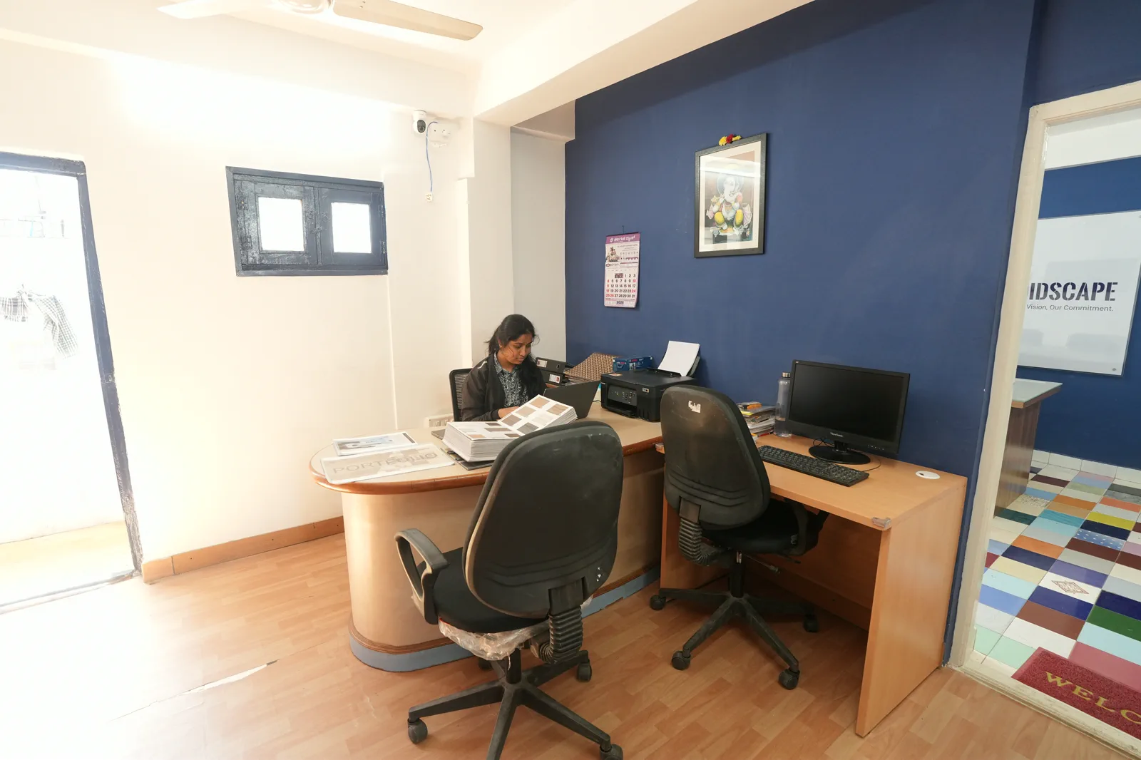 Reception area at the Candidscape studio on New BEL Road, Bangalore, with a curved front desk, task chairs and timber-look flooring